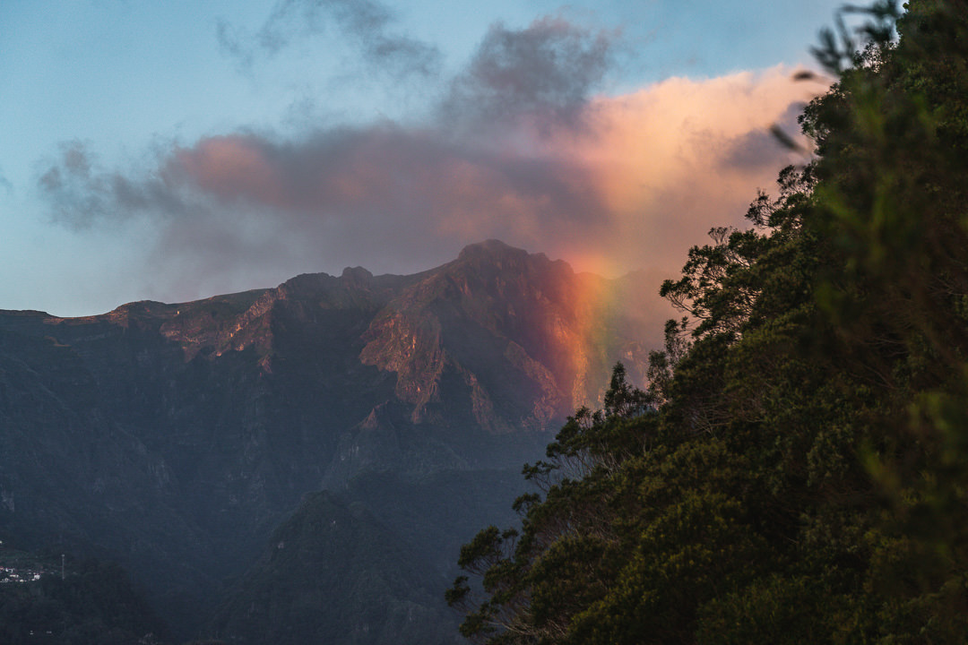 a rainbow appears in the sky over a mountain.