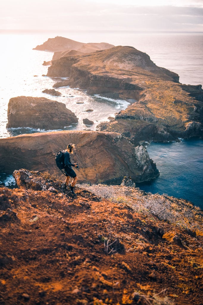 a person standing on top of a hill next to the ocean.