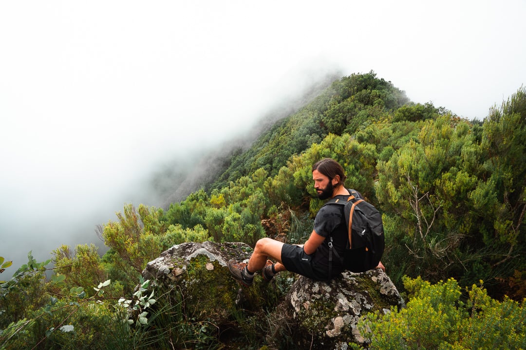 a man with a backpack sitting on a rock.