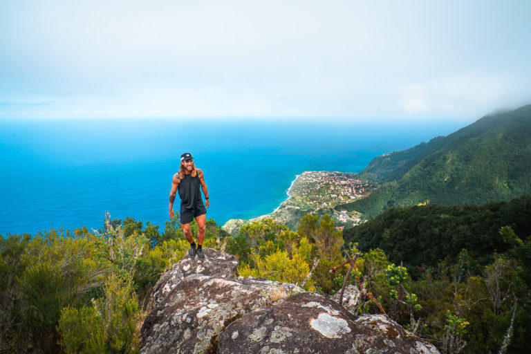 a man standing on top of a rock next to the ocean.