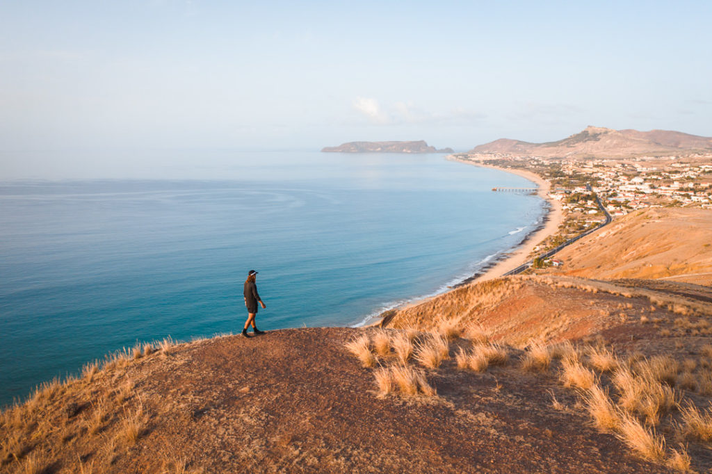 a man standing on top of a hill next to the ocean.