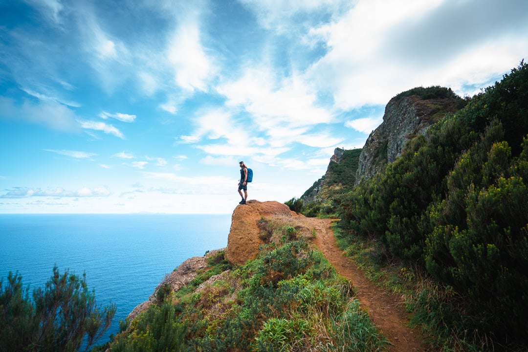 a man standing on top of a cliff next to the ocean.