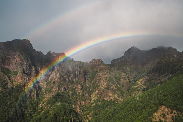 a rainbow over a mountain with a rainbow in the sky.