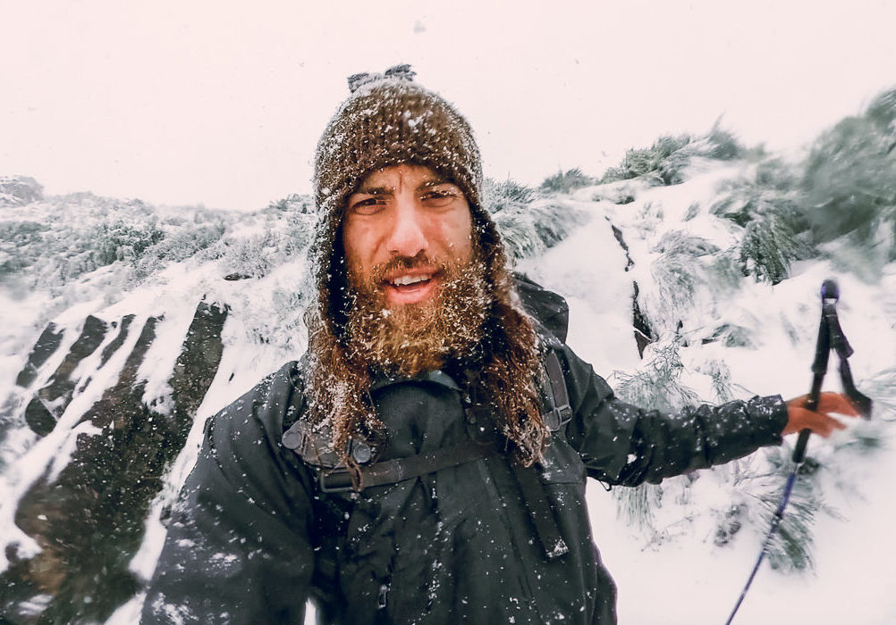 a man with a beard wearing skis in the snow.