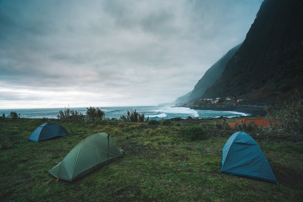 a couple of tents sitting on top of a lush green hillside.