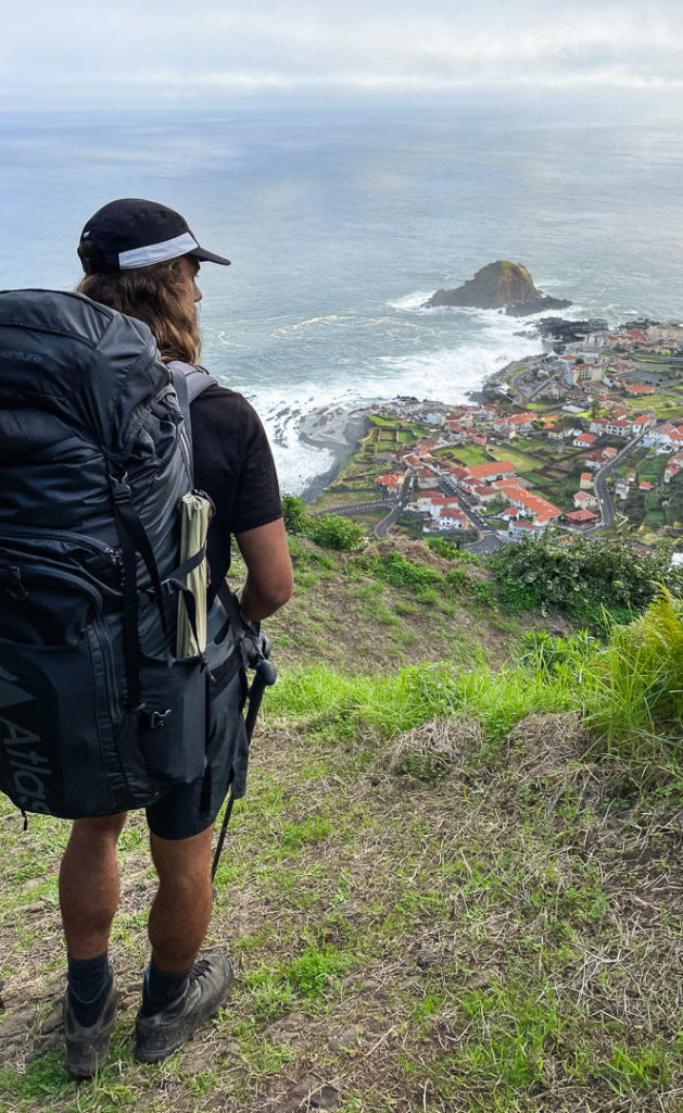a man with a backpack looking at the ocean.