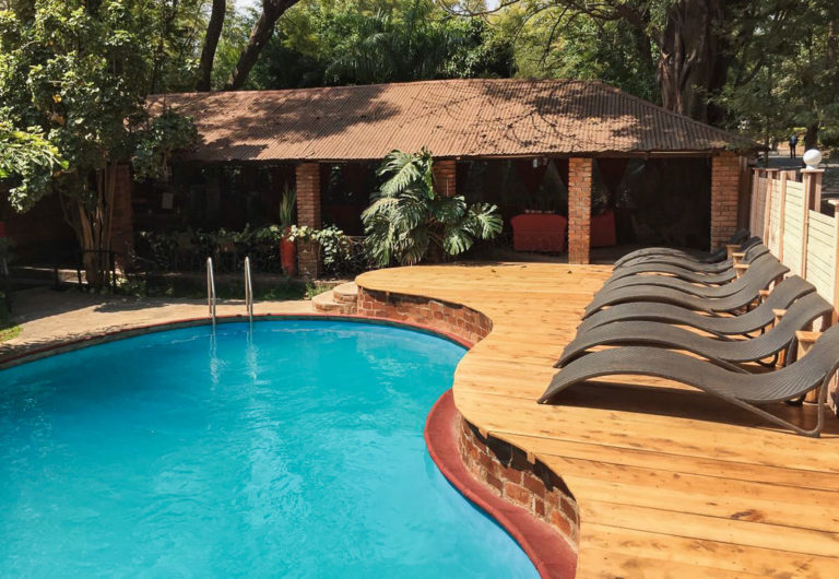 a pool with a wooden deck and lounge chairs next to it.