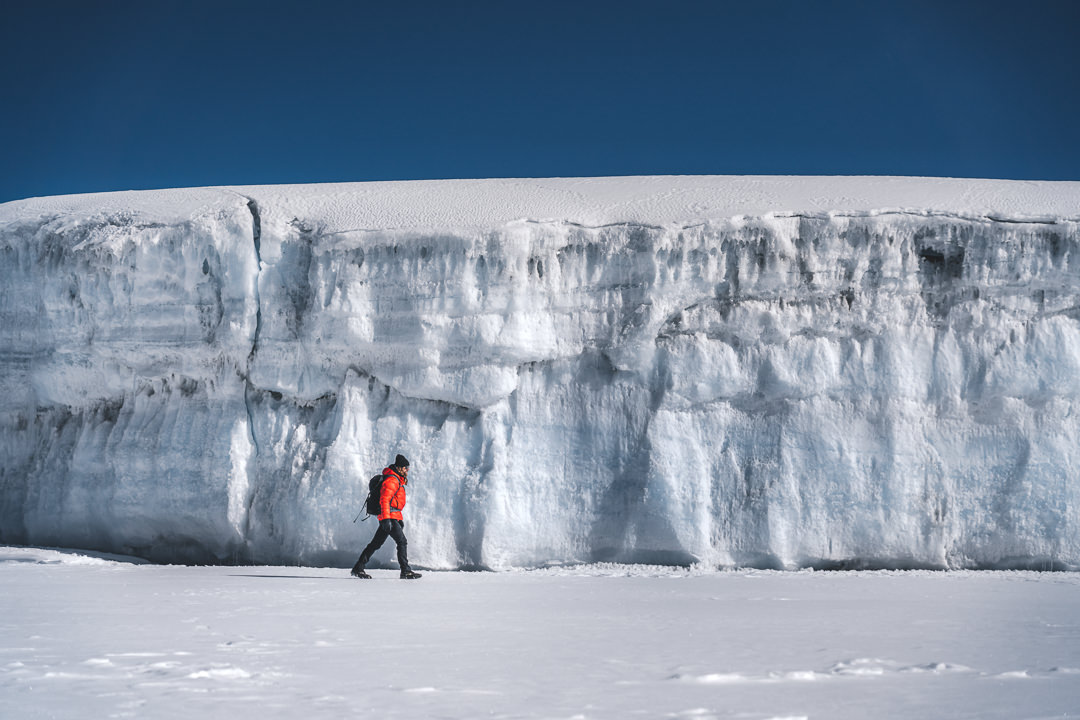 a man walking across a snow covered field.