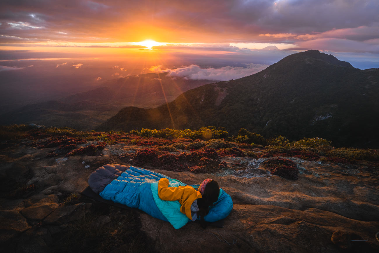a person laying on a rock with a sleeping bag