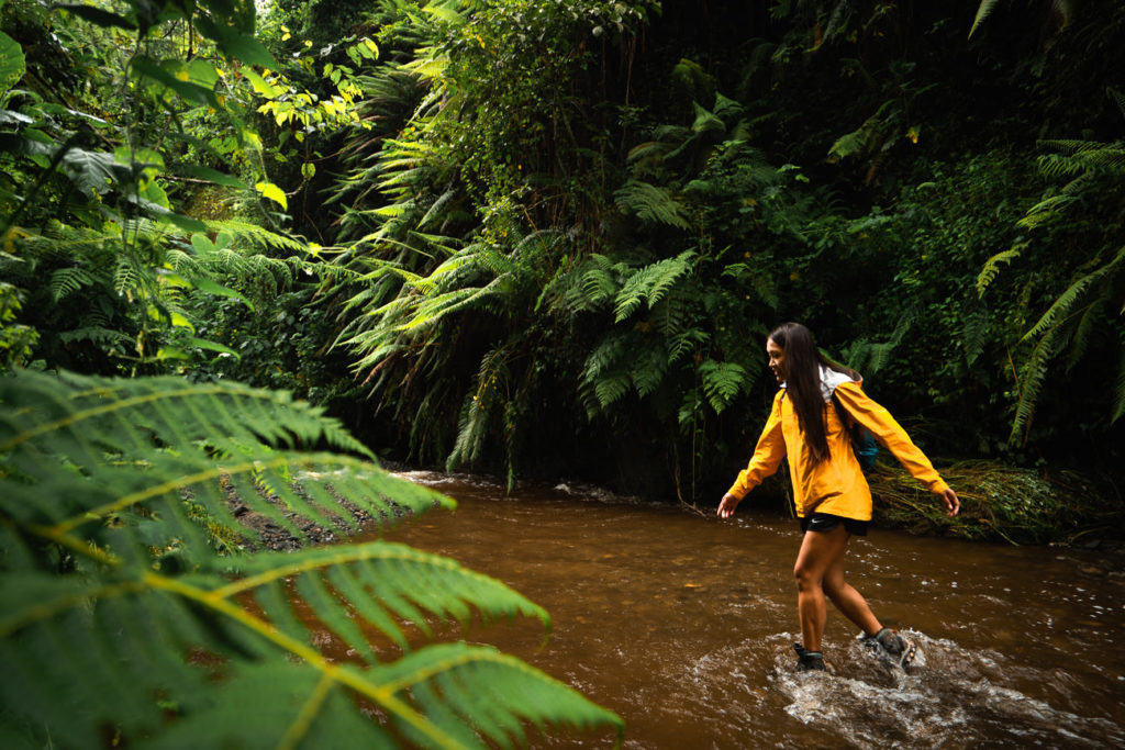 a woman in a yellow rain jacket crossing a river