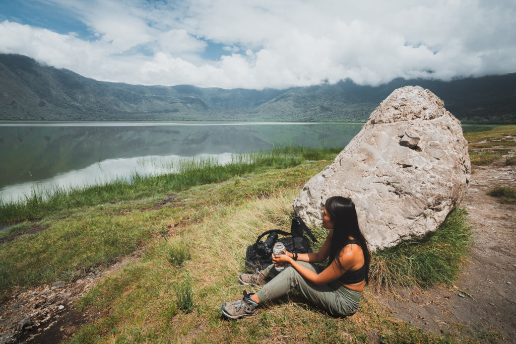 a woman sitting on the ground next to a large rock