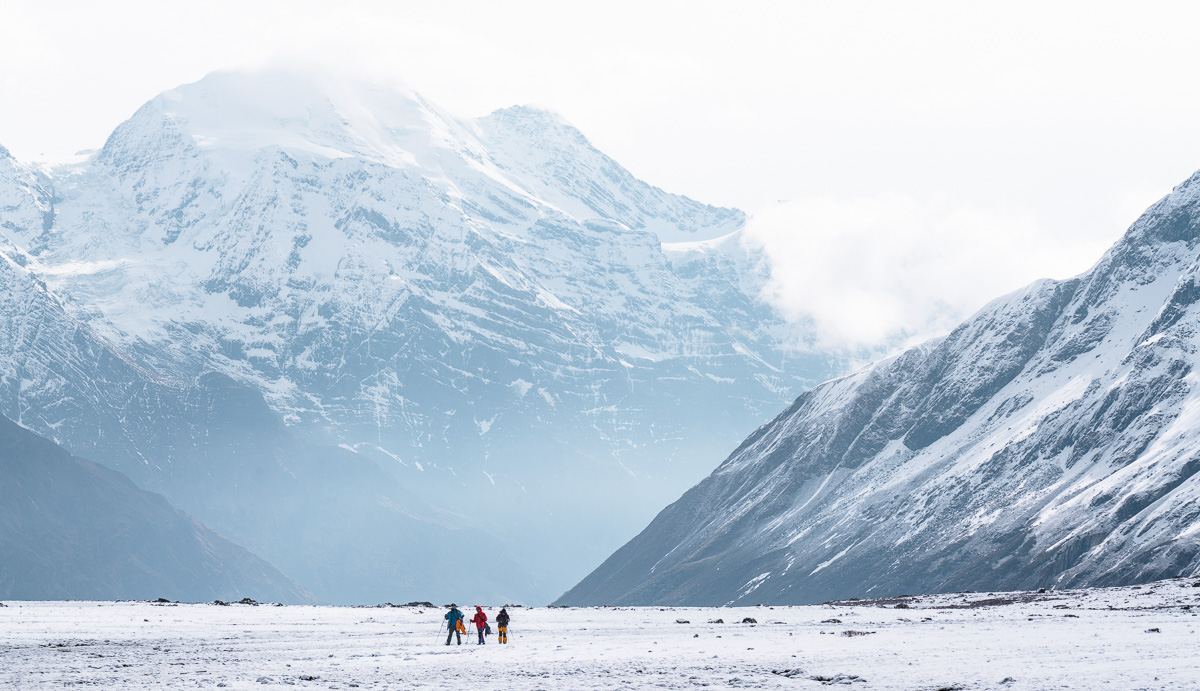 a group of people standing in front of a snow covered mountain