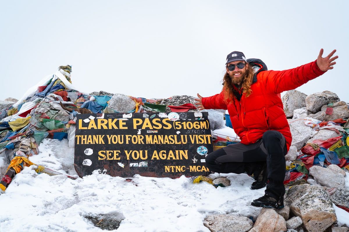 a man sitting on top of a pile of snow next to a sign