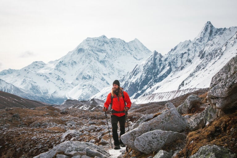 a man in a red jacket hiking up a mountain