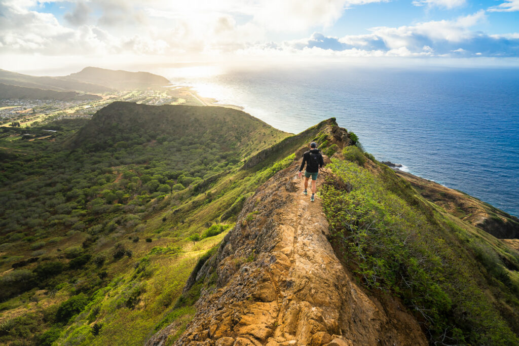 a person walking up a hill next to the ocean