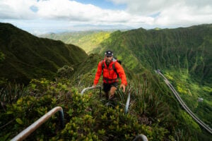 a man in an orange jacket hiking up a mountain