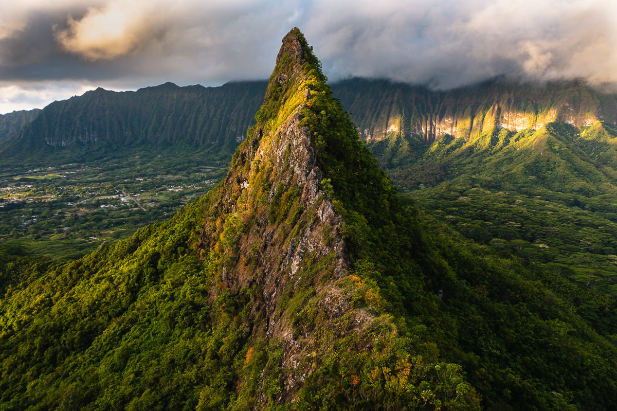 a very tall mountain surrounded by lush green trees