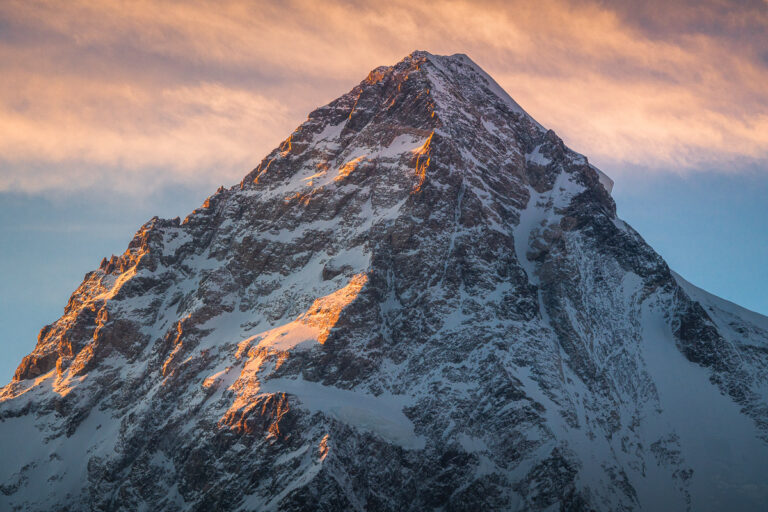 a very tall snow covered mountain under a cloudy sky