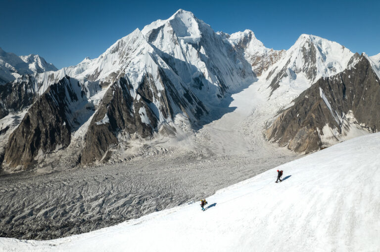 a couple of people riding skis down a snow covered slope