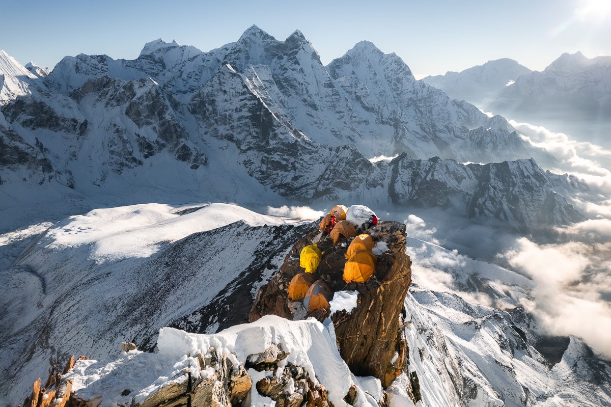 a group of people sitting on top of a snow covered mountain