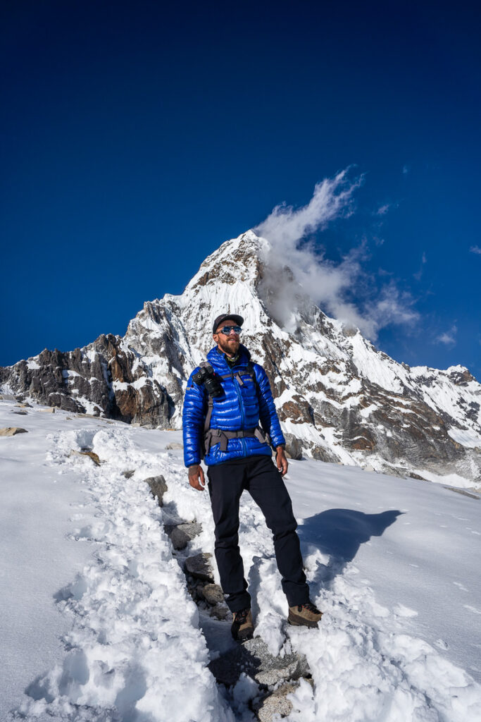 a man standing in the snow in front of a mountain