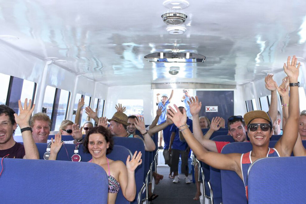 a group of people riding on a bus with their hands in the air