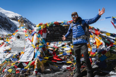 a man standing on top of a mountain next to a pile of flags