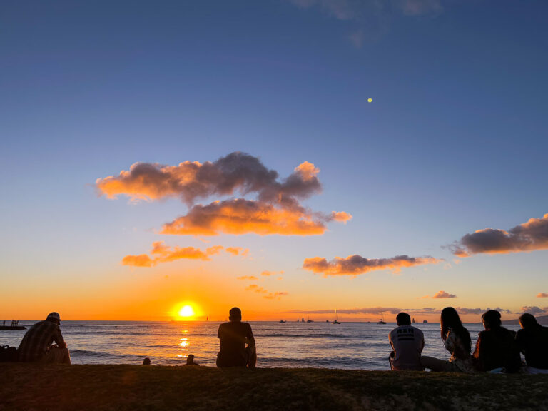 a group of people sitting on top of a sandy beach