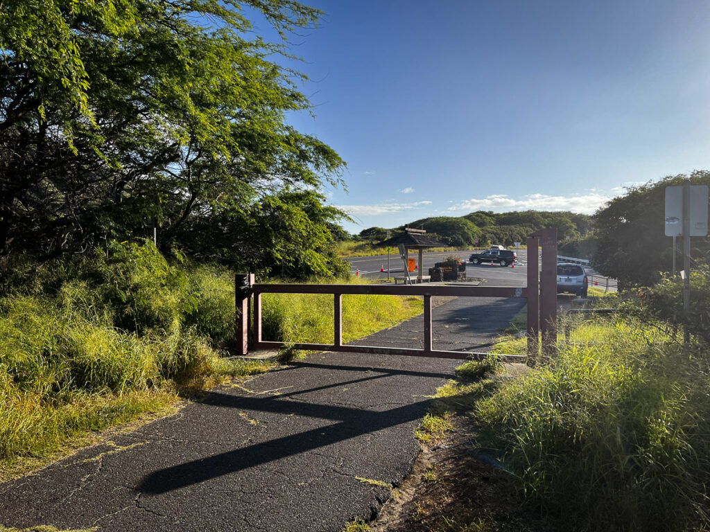 a road with a gate leading to a parking lot