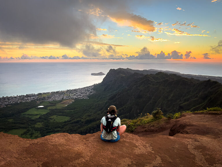 a person sitting on top of a mountain overlooking the ocean