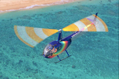 a colorful helicopter flying over the ocean