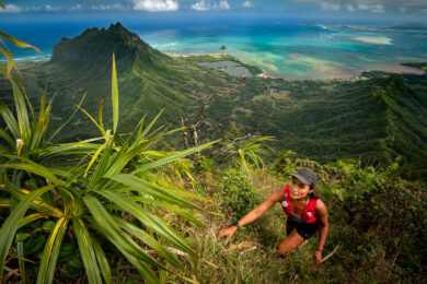a man hiking up a hill with a view of the ocean