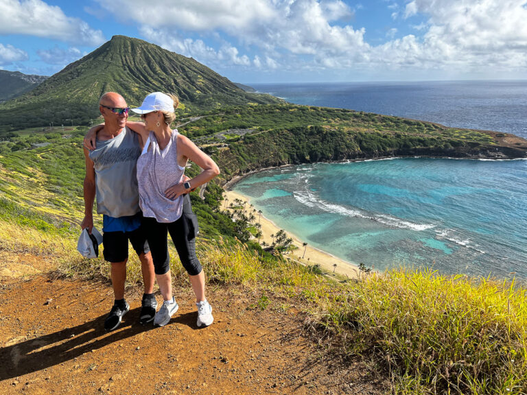 a man and a woman standing on a hill next to the ocean