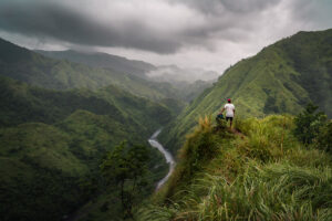 a man standing on top of a lush green hillside