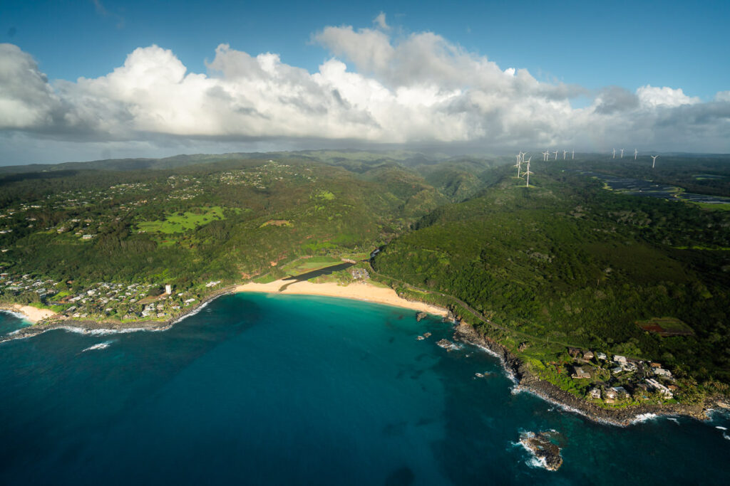 an aerial view of a lush green hillside next to the ocean.
