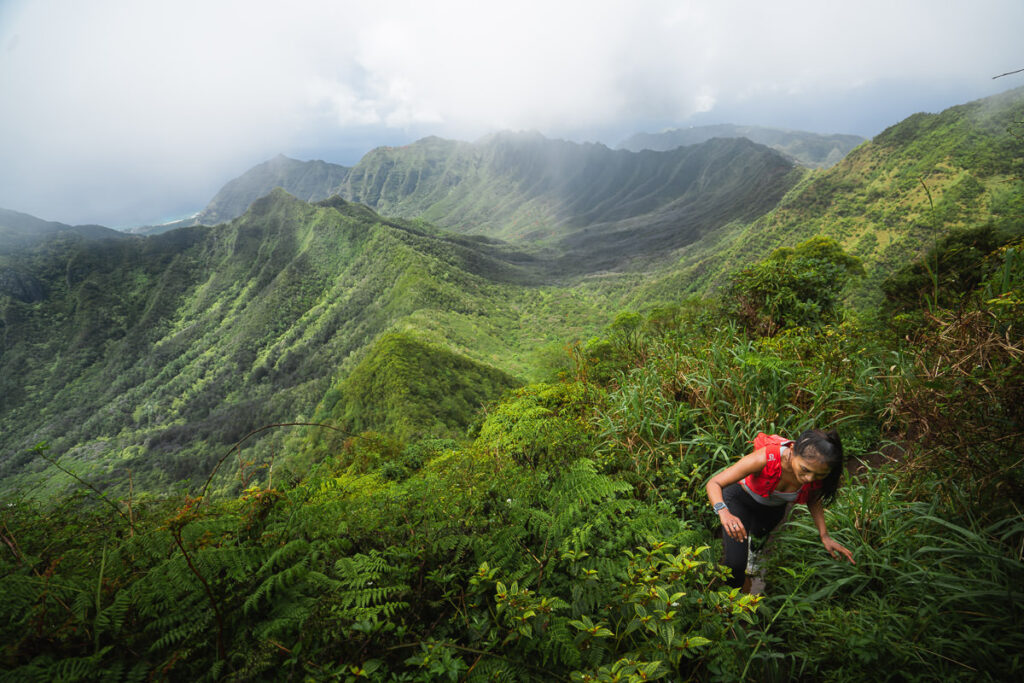 a man hiking up a steep mountain in the jungle.