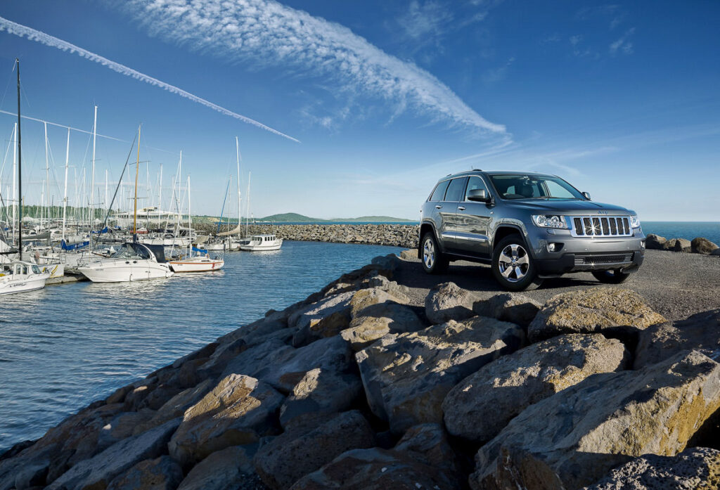 a jeep parked on a rocky shore next to a body of water.