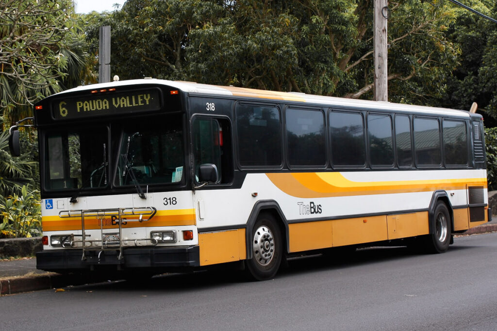 a yellow and white bus driving down a street.