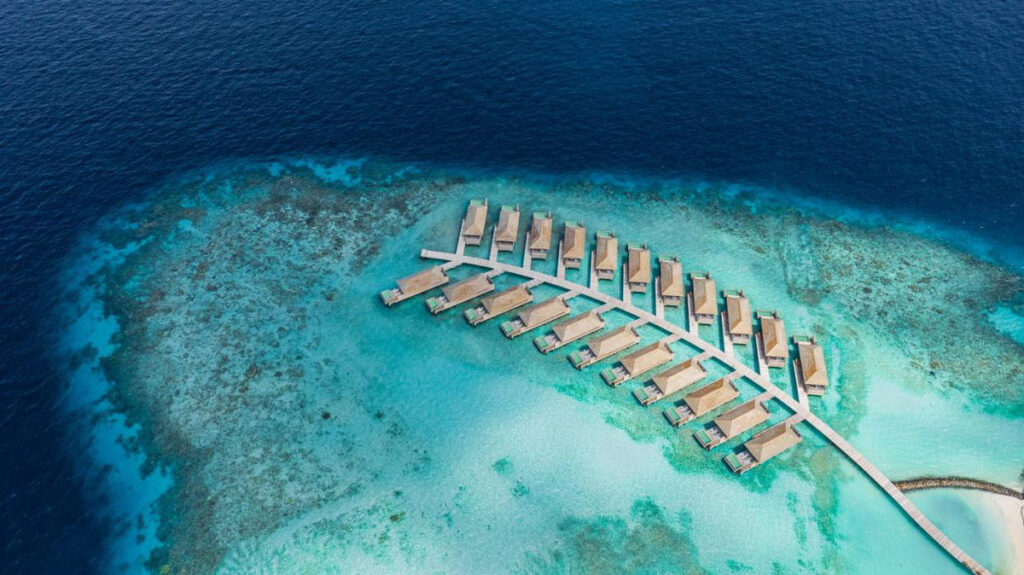 An adults-only resort in the Maldives viewed aerially amidst the oceanic surroundings.