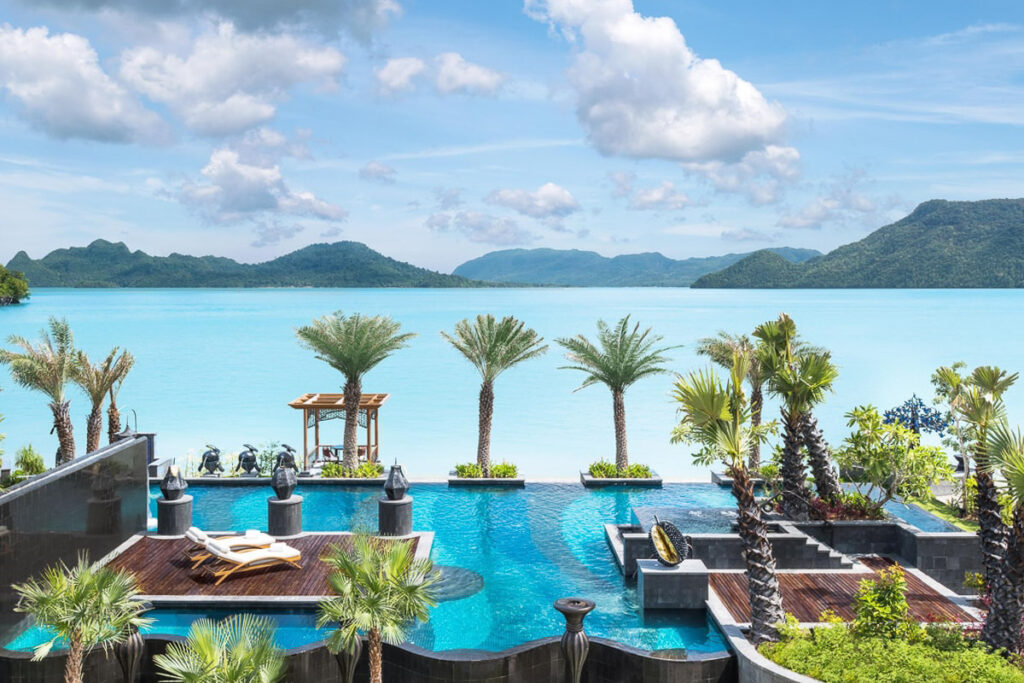 An over-water swimming pool with palm trees in Malaysia.