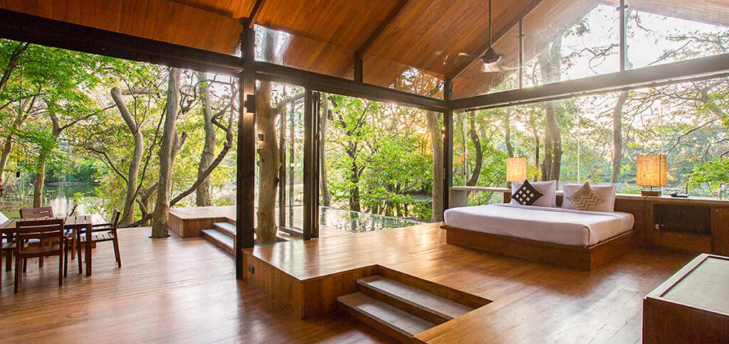 A Sri Lankan eco lodge bedroom featuring wooden floors and large windows.