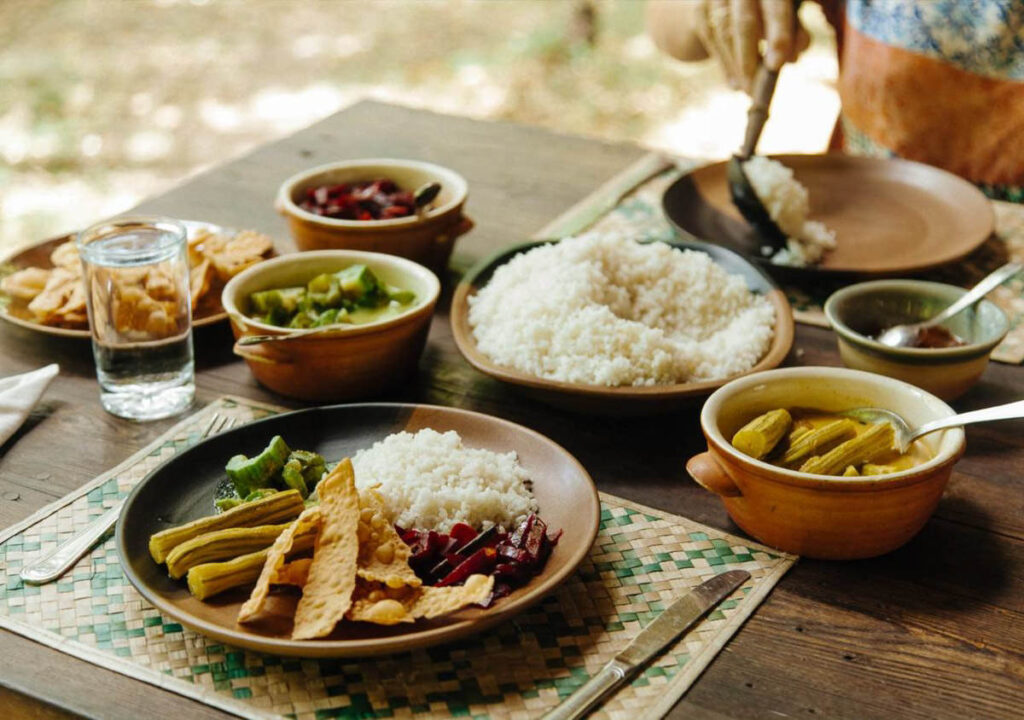 A table at eco lodges in Sri Lanka, topped with plates of food and bowls of rice.