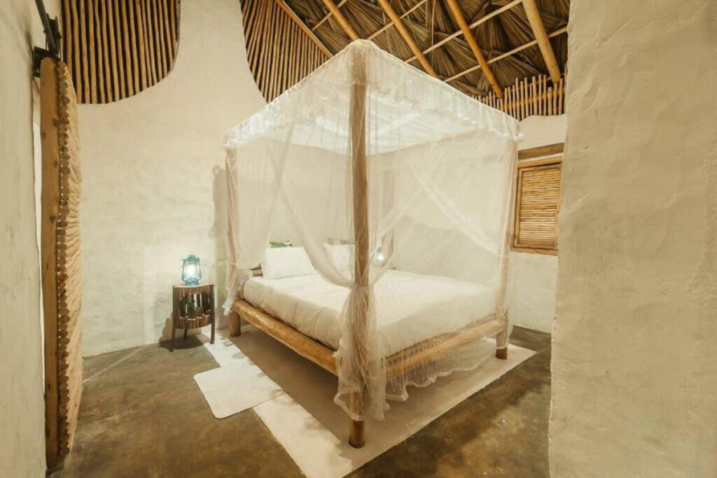 An eco lodge in Sri Lanka with a white canopied bed.
