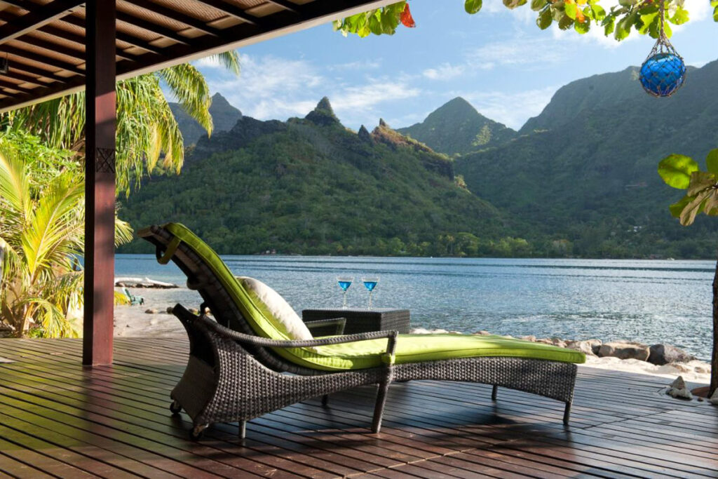a lounge chair on a wooden deck overlooking a lake.