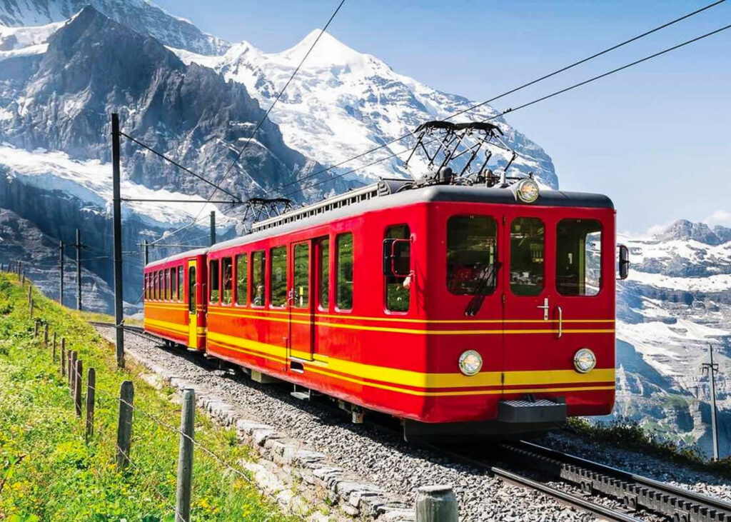 a red and yellow train traveling through the mountains.