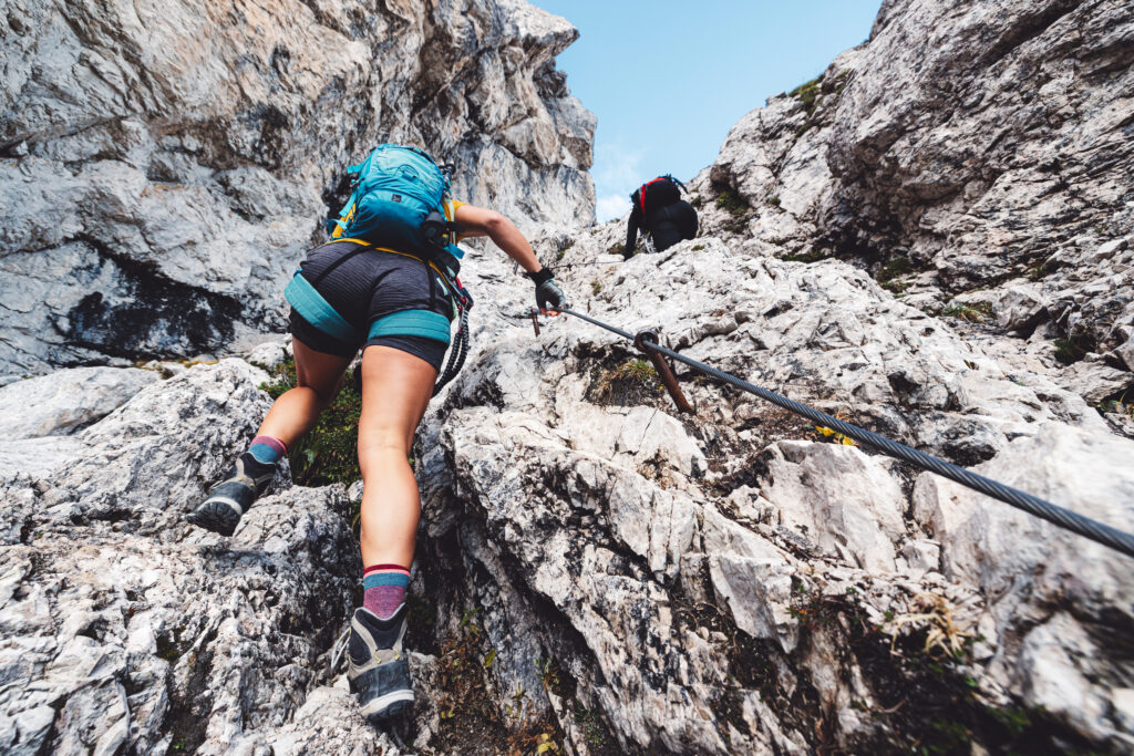 A woman is climbing up a rocky mountain.