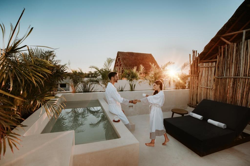 A couple in robes standing next to a pool at sunset.