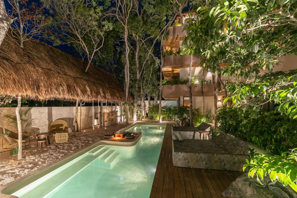 A pool with a thatched roof at night.