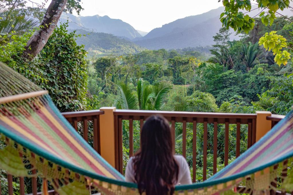 A woman sits in a hammock overlooking the jungle.