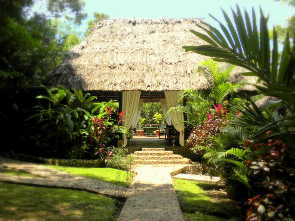 A thatched hut in the middle of a lush tropical garden.